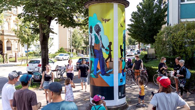 Kunstinteressierte an der Säule 8 mit dem Kunstwerk „Quest for Truth“ von DOME im achteintel—LitfassMuseum